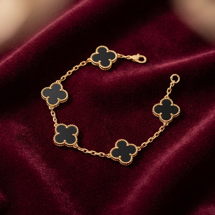 Gold-tone reversible clover link bracelet with black clover motifs arranged on deep burgundy velvet