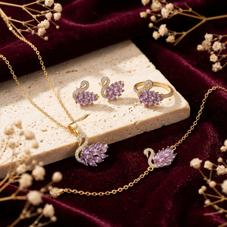 Swan jewellery set on burgundy velvet beside cream travertine